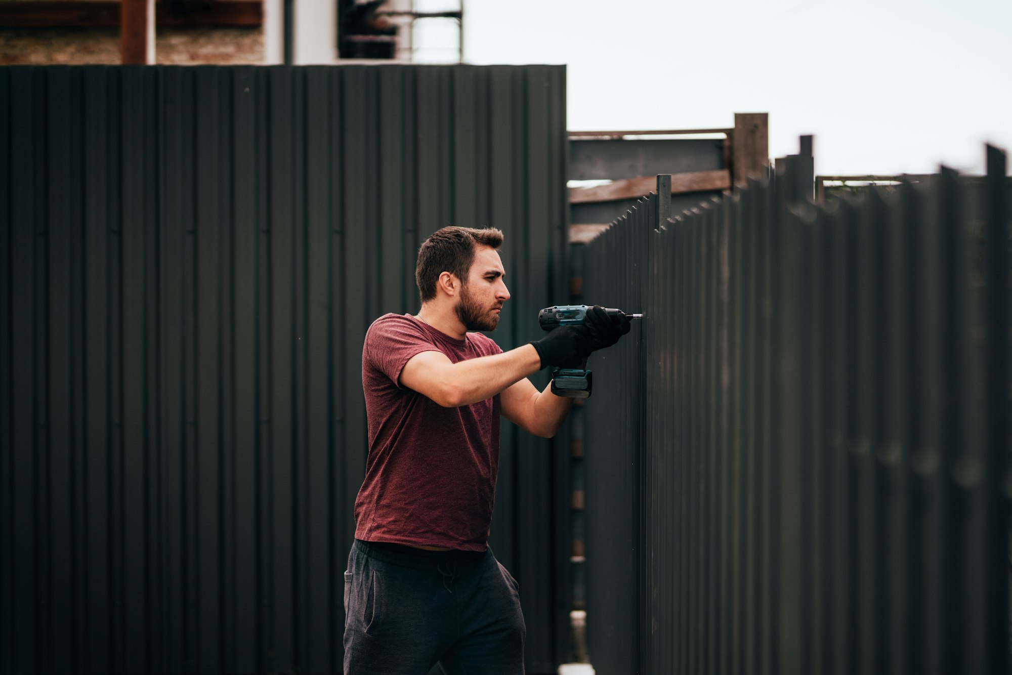 Industrial construction handyman using screwdriver for installing fence