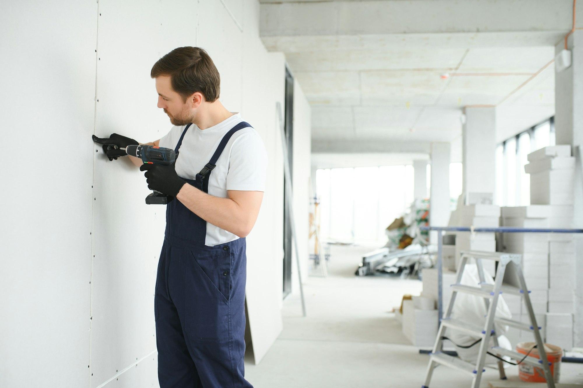 Worker builder installs plasterboard drywall at a construction